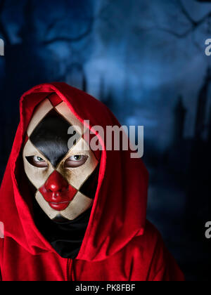 Femme masquée dans un sombre cimetière, vérifié vénitien masque complet halloween carnaval nuit bleu foncé Banque D'Images