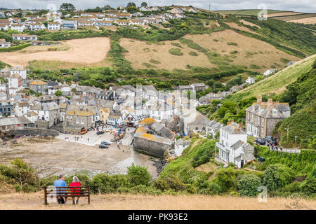 Un couple profiter de la vue depuis un banc haut au-dessus de port Isaac en Cornouailles du Nord. Banque D'Images