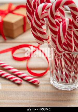 Le temps de Noël. Des cannes de bonbon dans un verre, fond en bois Banque D'Images