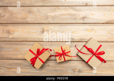 Le temps de Noël. Boîtes cadeaux avec ruban rouge sur fond de bois, copie espace, vue du dessus Banque D'Images