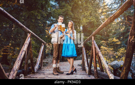 La femme et l'homme à la bière debout sur bridge en Bavière Banque D'Images