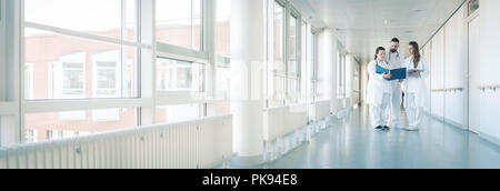 Trois médecins sur couloir de l'hôpital ayant courte réunion Banque D'Images
