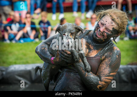 Une femme couverte de boue à la Plaine des jeux tient son chien boueux sale dans la boue wrestling pit Banque D'Images