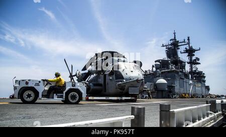 La Mer de Mindanao - Marines des États-Unis avec Marine à rotors basculants moyen (VMM) de l'escadron 166, Renforcée 13e Marine Expeditionary Unit (MEU), et les marins de la marine américaine avec les Essex Groupe amphibie (ARG) déplacer un CH-53E Super Stallion de VMM-166 en position pour le décollage à bord de la classe Wasp-navire d'assaut amphibie USS Essex (DG 2), pendant les opérations de recherche et sauvetage maritime manquant a fixé à la 13e MEU pendant un déploiement régulier de la Essex ARG et 13e MEU, Août 12, 2018, 12 août, 2018. L'Essex ARG/ 13e MEU est actuellement déployée dans la 7e flotte zone d'opérations. (U. Banque D'Images