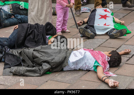 Glasgow, Scotland, UK - 17 juin 2012 : Les Syriens protester contre Bachar al-Assad crimes de guerre près de Donald Dewar statue. Les enfants faisant semblant d'être tués par République Banque D'Images