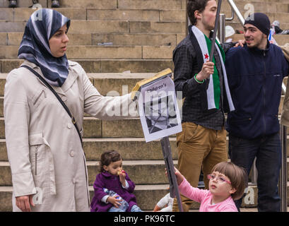 Glasgow, Scotland, UK - 17 juin 2012 : Les Syriens protester contre Bachar al-Assad crimes de guerre près de Donald Dewar statue. Femme avec des enfants et d'affiches, d'autres hommes Banque D'Images