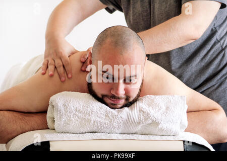 Studio de massage. Massage sportif. Massothérapeute masser les épaules d'un athlète masculin, le travail avec les muscles du cou. Les soins du corps. Massage homme. Banque D'Images