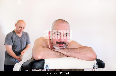 Détente Massage studio. Les gens apprécient un lit de massage. Massothérapeute travaillant avec patient, massant sa veaux. Les soins du corps. Massage homme. Banque D'Images