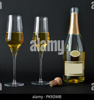 Deux verres de vin mousseux avec bouteille sur fond sombre Banque D'Images