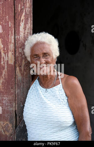 Portrait d'une vieille dame cubaine souriant debout dans sa maison porte Banque D'Images