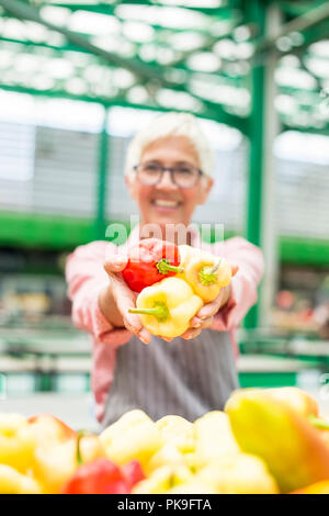 Portrait of senior woman vend des légumes bio sur le marché intérieur Banque D'Images