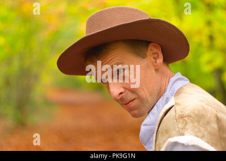 Un portrait d'un homme habillé comme un cow-boy à pied le long d'un chemin forestiers Banque D'Images