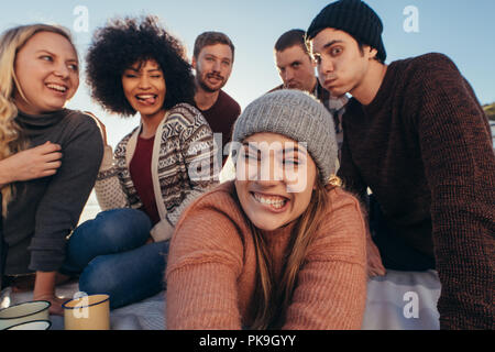 Groupe de jeunes faire des grimaces tout en tenant sur la plage selfies. Les jeunes bénéficiant d'ensemble à la plage faire un autoportrait. Banque D'Images