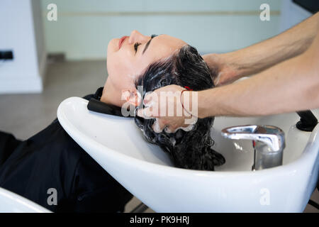 Belle brune se lave les cheveux dans un salon de beauté. Banque D'Images