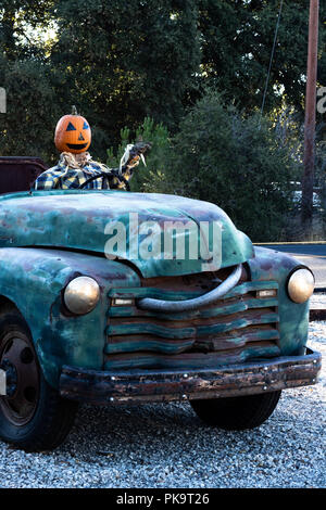 Accueillant, souriant, heureux, fun friendly tête de citrouille épouvantail conduisant un vieux camion à un halloween fête des récoltes à l'automne Banque D'Images