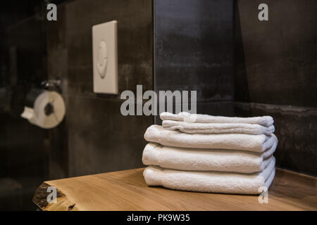 Salle de bains la nature morte, les serviettes blanches sur la table de bois et papier toilette Banque D'Images