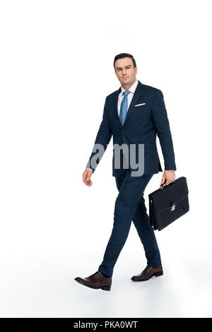 Sur toute la longueur du businessman with briefcase walking and looking at camera on white Banque D'Images