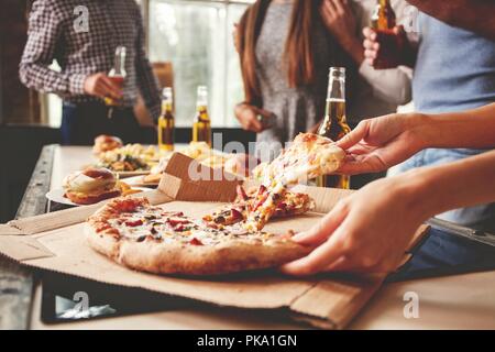 Les amis de prendre des tranches de pizza savoureuse de la plaque, vue en gros plan. Banque D'Images