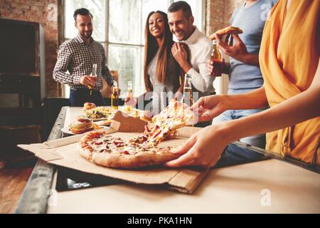 Les amis de prendre des tranches de pizza savoureuse de la plaque, vue en gros plan. Banque D'Images