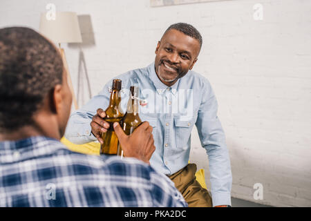 Cropped shot of happy father with adult son cliquetis de bouteilles de bière à la maison Banque D'Images