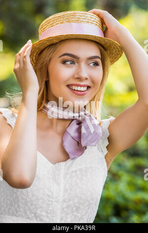 Beautiful smiling blonde girl wearing hat en osier avec ruban et à la voiture en stationnement Banque D'Images