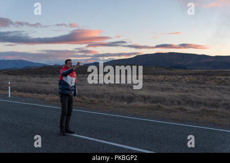 L'homme prend une photo de la route au coucher du soleil Banque D'Images