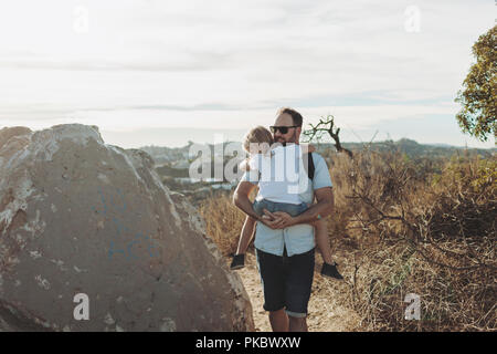 Un père porte sa jeune fille sur un sentier de randonnée ; Los Angeles, Californie, États-Unis d'Amérique Banque D'Images