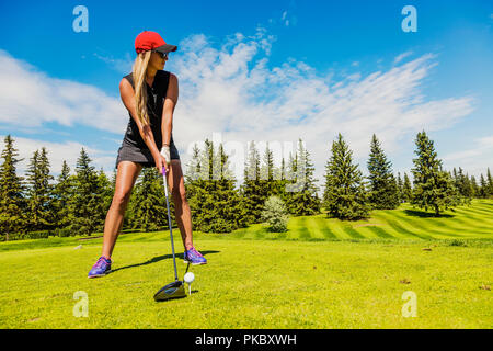 Un golfeur féminin s'aligne son conducteur de la balle de golf sur un raccord en t ; Edmonton, Alberta, Canada Banque D'Images