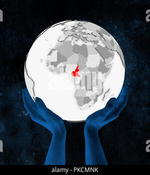 Le Cameroun en rouge sur blanc globe tenue en mains dans l'espace. 3D illustration. Banque D'Images