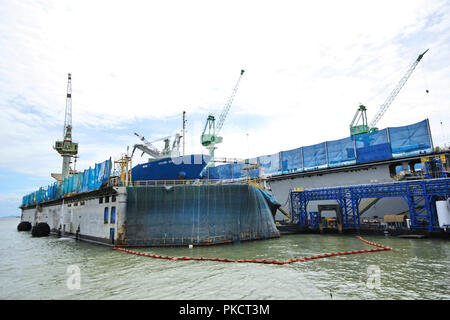 Grand angle de visualisation de grands navires commerciaux en floating dock de réparation. La grue de chantier naval en tissu bleu fournir et déposer le réservoir d'huile de la bouée. À Banque D'Images