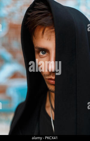 Portrait d'un bel homme dans un capot noir. Face Cachée. Banque D'Images