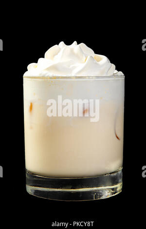 D'une couleur opaque crémeux, milk-shake dans un verre bas, avec de la crème fouettée et des cubes de glace. Vue de côté arrière-plan noir isolé. Verre pour le menu restau Banque D'Images