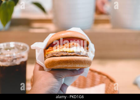 Hands holding fresh délicieux hamburgers avec du café. Banque D'Images