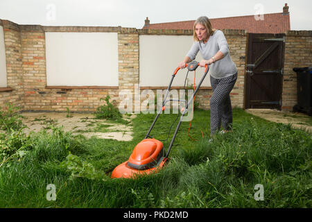 femme fauchant une pelouse d'herbe surcultivée Banque D'Images