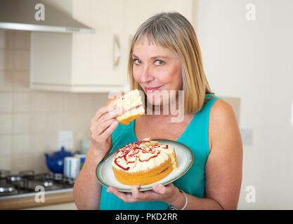 Femme mangeant un gâteau à la crème Banque D'Images