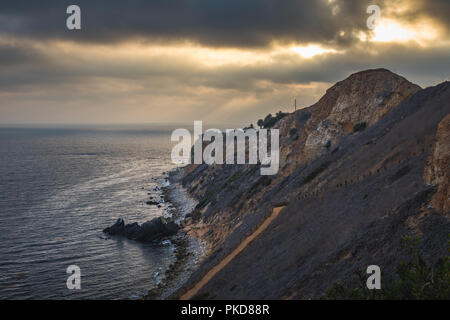 Superbe vue sur la côte de coucher du soleil à l'abrupte falaise de Pelican Cove Park sur un jour nuageux avec des faisceaux de lumière du soleil piquer à travers les nuages au-dessus de Point V Banque D'Images