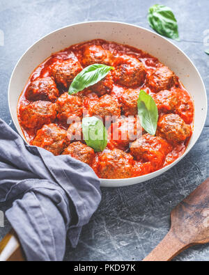Boulette de bœuf savoureux en sauce tomate avec des épices et de basilic frais sur une table de cuisine. La photographie alimentaire, vertical shot, une cuisine européenne. Banque D'Images