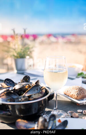 Moules dans une casserole et un verre de vin blanc froid. Délicieux dîner de fruits de mer dans un restaurant sur la plage. Copy space Banque D'Images