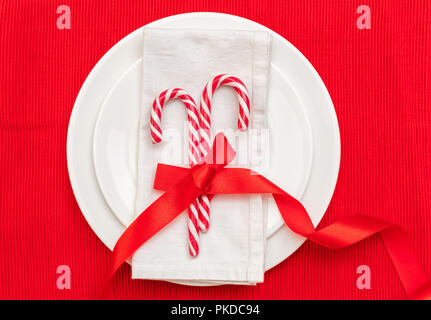 Réglage de la table de Noël. Des cannes de bonbon sur les plaques blanches et rouges, serviette, nappe en vue d'en haut Banque D'Images