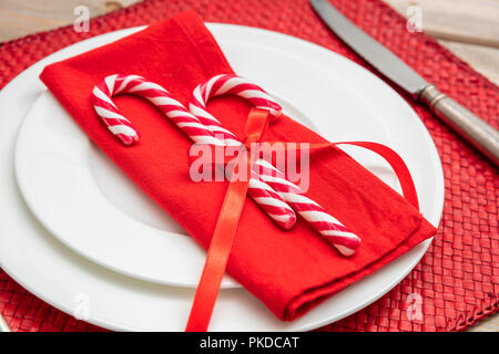 Réglage de la table de Noël. Des cannes de bonbon sur les plaques blanches et une serviette, tapis rouge, vue rapprochée Banque D'Images