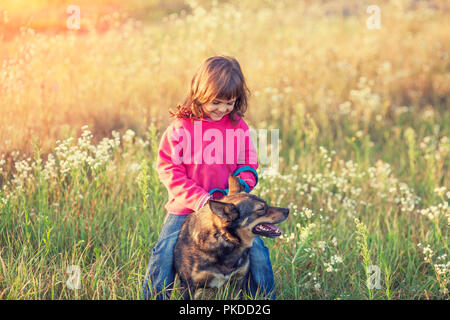 Happy little girl avec son chien jouant dans la prairie à l'automne Banque D'Images