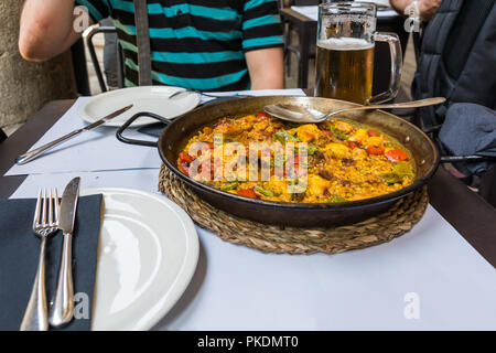 Le Plat traditionnel Espagnol - paella de poulet servi dans une poêle à frire sur nappe blanche. Riz, poulet et rouge vif et les légumes verts sont mélangés Banque D'Images