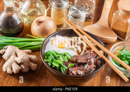 Nouilles Udon japonaise avec le boeuf, l'oeuf, l'oignon vert et de la soupe dans un bol brun Banque D'Images