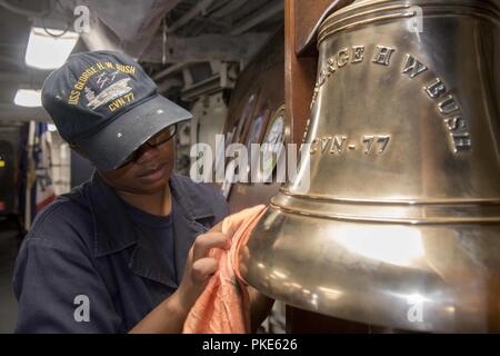 NORFOLK, Virginie (25 juillet 2018) Maître de Manœuvre Seaman Jordan Howard, de Pittsburgh, brille la cloche du navire au cours du poste de nettoyage à bord du porte-avions USS George H. W. Bush (CVN 77). Le bateau est dans le port de Norfolk, Virginie, en effectuant des exercices d'entraînement de routine pour maintenir l'état de préparation de l'opérateur. Banque D'Images