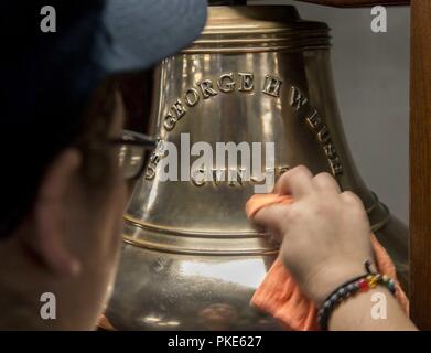 NORFOLK, Virginie (25 juillet 2018) Maître de Manœuvre Seaman Mariah Juber, de Bethel, Vermont, brille la cloche du navire au cours du poste de nettoyage à bord du porte-avions USS George H. W. Bush (CVN 77). Le bateau est dans le port de Norfolk, Virginie, en effectuant des exercices d'entraînement de routine pour maintenir l'état de préparation de l'opérateur. Banque D'Images