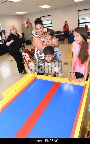 Daniel - Pix-geeks.com, 5, prend son tour lancer skeetball avec sa soeur Mia, 10, tandis que leur mère Marie et soeur Lexi, 1, montres. La famille - Pix-geeks.com rejoint d'autres membres de la communauté de Fort Drum au bâtiment de service communautaire de l'armée le 26 juillet au cours de la célébration de l'anniversaire de l'AEC. ( Banque D'Images