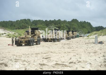 VIRGINIA BEACH, en Virginie (25 juillet 2018) Des soldats du 11e bataillon de transport lourds Oshkosh préparer leur mobilité élargie (camions tactiques HEMTT) de sortir de l'Utah Beach après le débarquement de l'amélioration du système d'allège la Marine (INLS) Causeway Ferry, tout en participant à l'exercice Trident Soleil à bord 18 expéditionnaire conjointe Base Little Creek - Fort Story. Sun 18 Trident est un prépositionnement maritime force (MPF) opération destinée à assurer la formation de personnel de réserve en ce qui concerne le déchargement dans le flux de véhicules militaires et de l'équipement. Banque D'Images