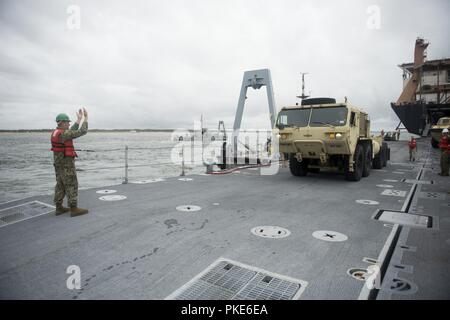 VIRGINIA BEACH, en Virginie, un membre de l'Roll on/Roll Off Installation de décharge (RRDF) guides de l'équipe de l'armée américaine une mobilité élargi lourds Oshkosh (Tuck tactique HEMTT) à l'attente de l'amélioration du système d'allège la Marine (INLS) au cours de la Causeway Ferry Soleil Trident exercice 18. Sun 18 Trident est un prépositionnement maritime force (MPF) opération destinée à assurer la formation de personnel de réserve en ce qui concerne le déchargement dans le flux de véhicules militaires et de l'équipement. Banque D'Images