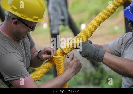 La CPS. Jean Mitchell, un ingénieur de construction avec la 377e compagnie du génie, couper le tube en plastique pour couvrir le câblage en acier de 25 mètres de l'aire de répartition à la zone d'entraînement Local Keystone, situé à Conneaut Lake, New York, le 25 juillet. Plus de 100 soldats ont aidé à la restauration de la voûte de la formation locale. Banque D'Images