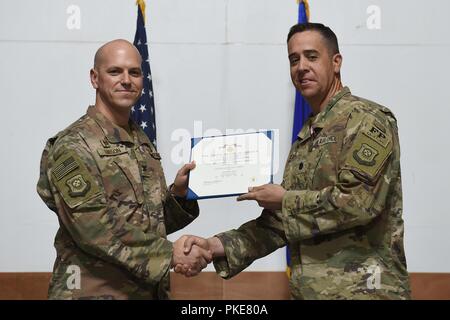 Le colonel Scott Gibson, commandant du groupe expéditionnaire de la 407e et président de séance, présente la Médaille du service méritoire au Lieutenant-colonel Glenn Cameron lors d'une cérémonie de passation de commandement dans un endroit inconnu en Asie du Sud-Ouest, 27 juillet 2018. Cameron a quitté le commandement de la Force expéditionnaire du 407e Escadron de génie civil au major Shane Patty. Banque D'Images